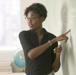 A teacher talking to the class while standing at the blackboard
