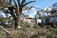 Broken tree limbs and damaged house caused by a tornado