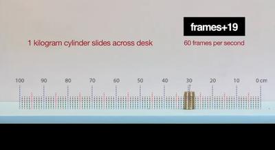 screen shot a a metal cylinder sliding across a table
